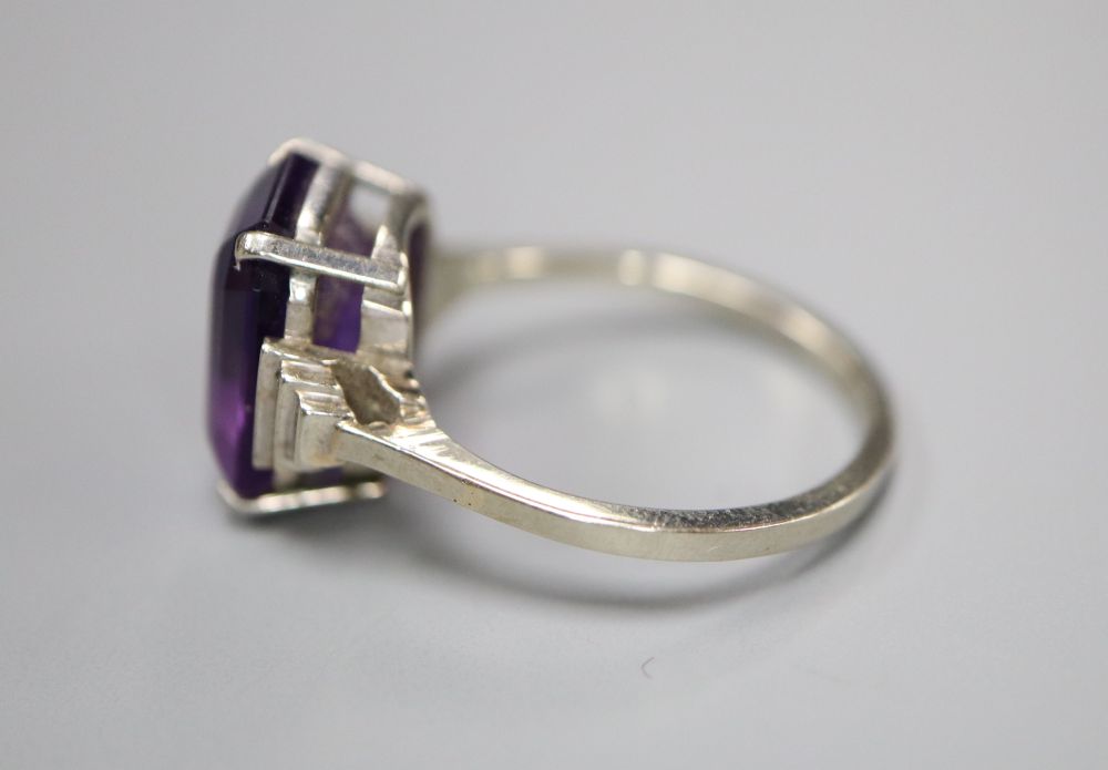 An Art Deco style 9ct white metal and emerald cut amethyst set dress ring, with stepped shoulders, size P, gross 3.8 grams.